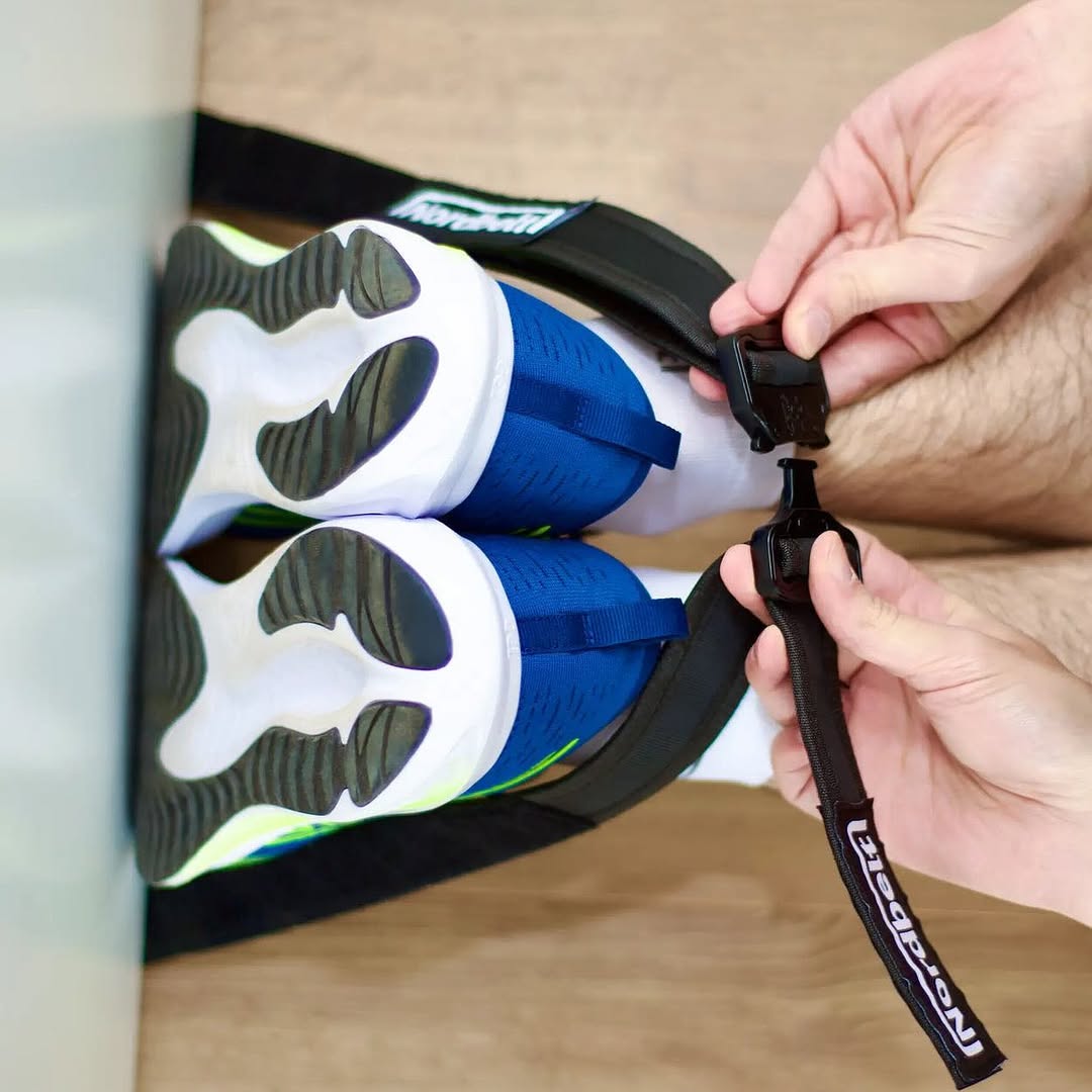 Hände stellen den Knöchelgurt über zwei Schuhen an einer Tür ein.